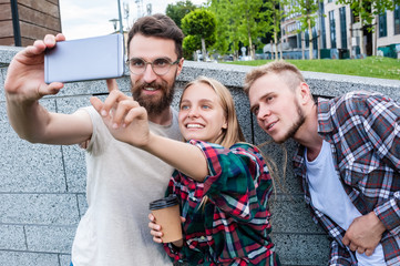 happy young friends taking selfie with smartphone on street