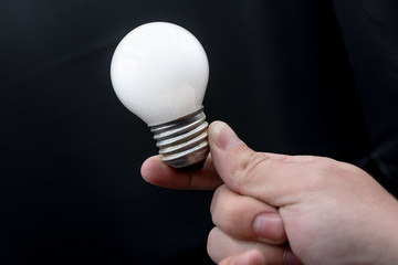 Hand holding a bulb light creative idea concept power electric  in a black background innovation technology equipment inspiration glass isolated finger perspective develop