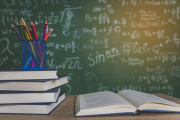 Back to school supplies. Books and blackboard on wooden background.