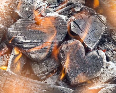 Hot coals and burning woods in the form of human heart. Glowing and flaming charcoal, bright red fire and ash. .Close-up, top view.