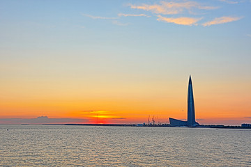 The Lahta center skyscraper buidling on the shore of Finish bay near Petersburg city in the mouth of Neva river in the rays of setting sun. The beautiful orange and red urban landscape 