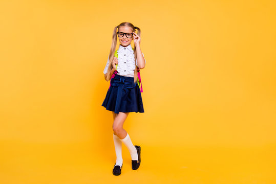 Full length, legs, body, size portrait of beautiful, charming, gorgeous small blonde girl in skirt stand isolated on shine yellow background with copy space for text corrects glasses