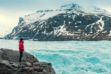 Asian young man in red jacket looking the glacier  in iceland - Powered by Adobe