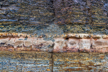 The vertical natural cliff with solid sedimentary layer and breccia