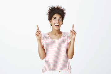 Happy carefree african-american woman with combed curly hair in striped t-shirt, looking and...