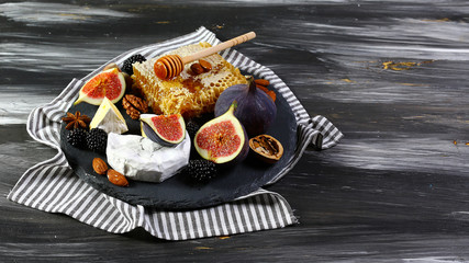Camembert cheese with honey, figs, walnuts on stone board on a dark background, Flat lay, Copy space