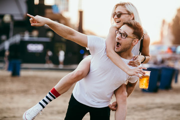 Young couple piggy backing at music festival 