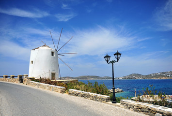 Fototapeta na wymiar Old traditional greek windmill in the street of Parikia