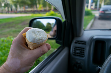the driver holds the ice cream while driving a car