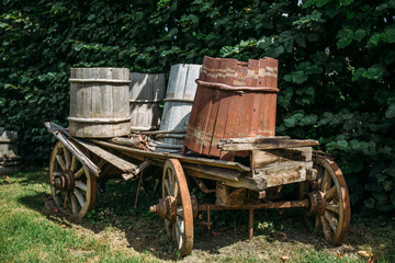 Fototapeta na wymiar Vintage wooden cart with wooden buckets in rural farm in sunny summer or autumn day