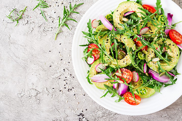 Diet menu. Healthy salad of fresh vegetables - tomatoes, avocado, arugula, radish and seeds on a bowl. Vegan food. Flat lay. Top view