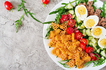 Pasta salad with fresh vegetables, eggs and tuna in a white bowl. Lunch food. Top view.  Flat lay