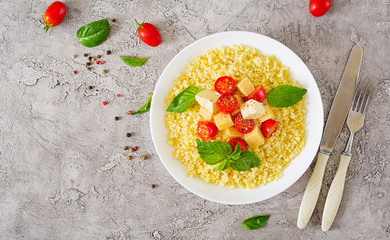 Millet porridge with cheese, butter and basil in white bowl. Tasty food. Breakfast. Top view. Flat lay