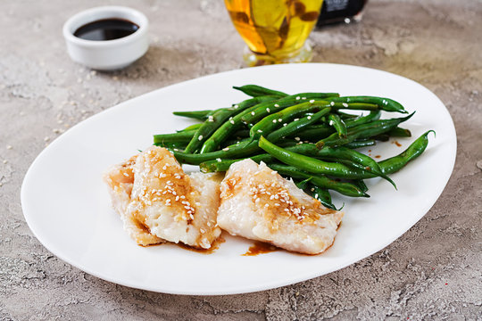Fish fillet served with soy sauce and green beans in white plate. Asian food.