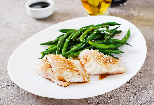 Fish fillet served with soy sauce and green beans in white plate. Asian food.