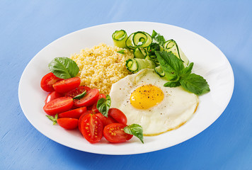 Healthy breakfast. Dietary menu. Millet porridge and tomato, cucumber salad and fried eggs.