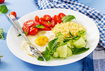 Healthy breakfast. Dietary menu. Millet porridge and tomato, cucumber salad and fried eggs.