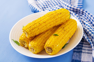 Boiled corn in white plate on blue background. Summer food.