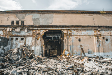 Ruined abandoned industrial building with large pills of concrete garbage, aftermath of natural disaster, hurricane, earthquake or war