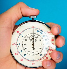 Close Up Of Hand Holding Stopwatch on Blue Blackground