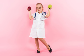 Fototapeta premium Little girl in doctor costume with apples