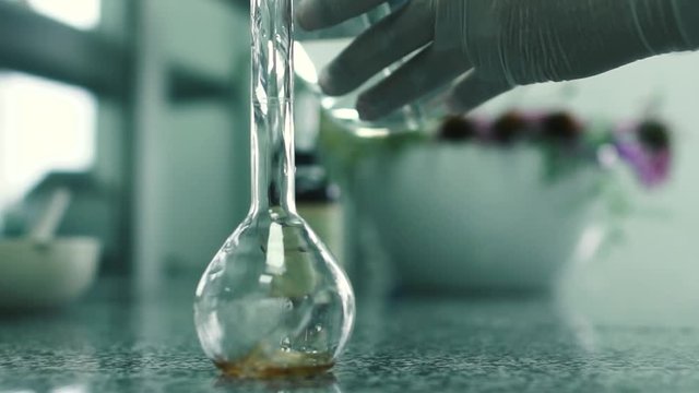 Laboratory assistant pours the water into the flask