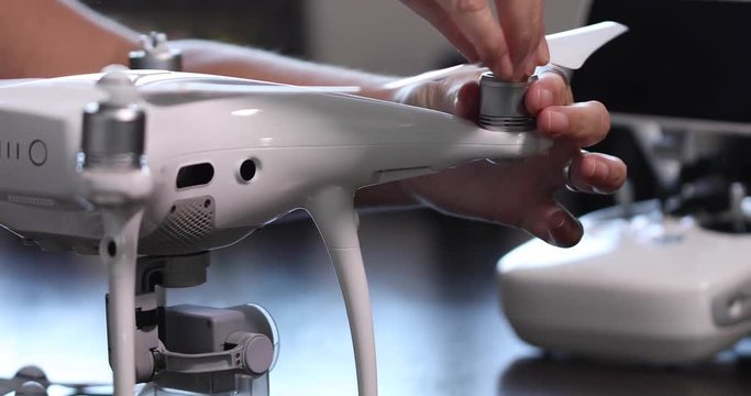 Pan Of Pilot Securing Propellars Onto Drone Quadcopter with Controller Behind