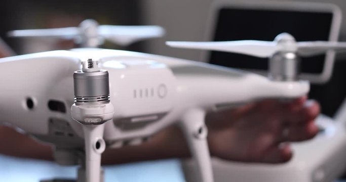 Pan Of Pilot Securing Propellars Onto Drone Quadcopter with Controller Behind