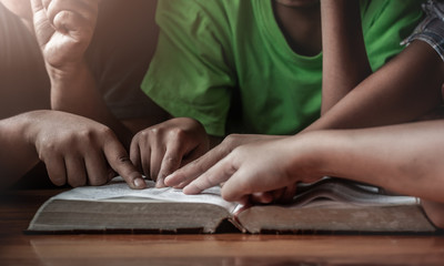 christian children group reading holy bible on table in home room