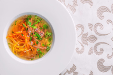 healthy beef broth with vegetables and meet served on white plate, product photography for restaurant and gastronomy