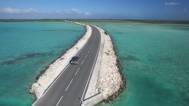 Car drives on tropical roadway in Turks and Caicos, aerial