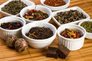 Aromatic Dried Tea Leaves in Bowls on Bamboo Mat