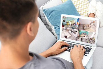Man in casual clothes using laptop on sofa at home