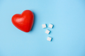 Cubes of sugar and red heart on a blue background
