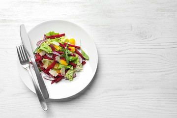 Plate with delicious beet salad on wooden background, top view