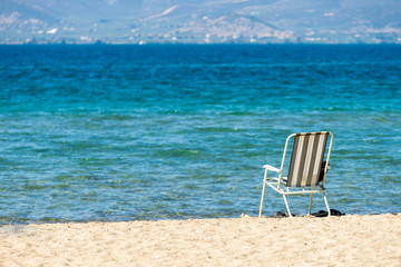 Deck chair on sand beach next to water