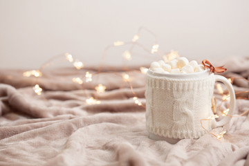 Hot chocolate with marshmallows on soft plaid background with Christmas lights. Perfect winter time treat.