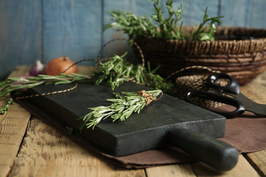 Wooden board with rosemary on table. Aromatic herbs