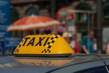 taxi cap on a car roof against the city