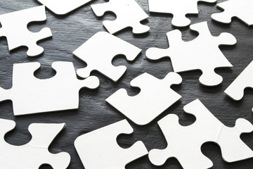 White puzzles folded in chaotic order on a dark table.