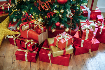 Christmas Gifts wrapped in classic red paper, background with xmas lights bokeh of blurred under Christmas tree. Copy space