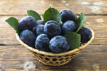 Plums in a basket on a wooden table.