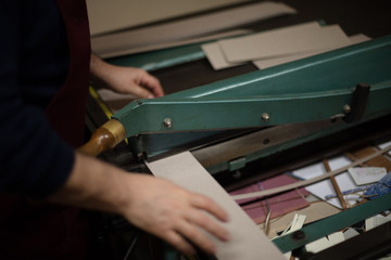 Man cutting paper and card on a large guillotine