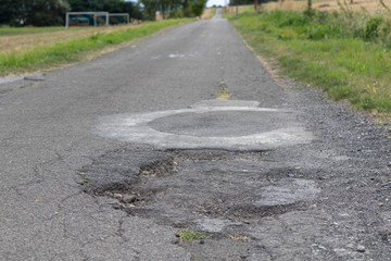 Pothole on a concrete way in a rural landscape