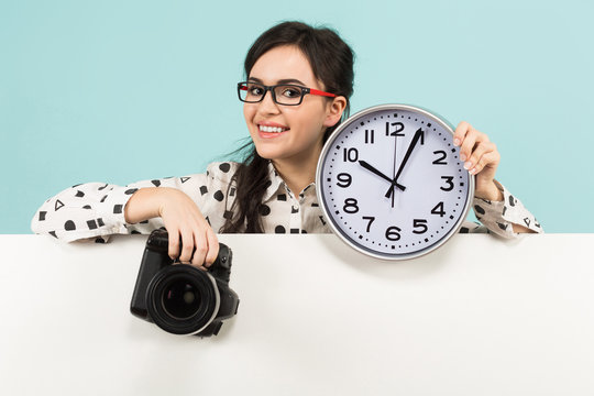 Young woman with camera and clocks