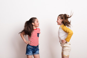 Small girls standing in a studio, looking at each other.