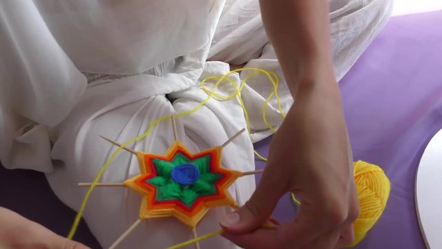Colored Colorful Hand Made Mandala Close Up. Creation Natural Closeup Macrame Meditation. Process Hand Made Mandala. Woman in White Clothes Making Mandala.