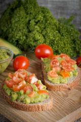 Avocado toast, cherry tomato and poached eggs on wooden background. Breakfast with vegetarian food, healthy diet concept.