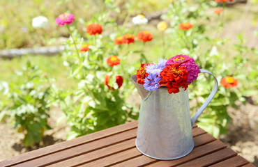 Metal pitcher full of brightly coloured flowers