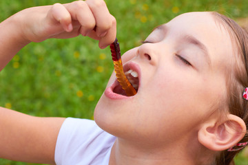 The child is eating a jelly worm.